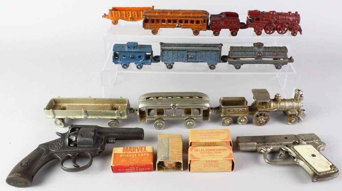 Toy Lot Cast Iron Trains & Cap Guns: Group of cast iron floor trains. Spit Fire Pistol and Stevens 6 Shot Rapid Load 1932 Cast Iron Revolver, and caps in boxes. Longest silver trains over 16 inches long.