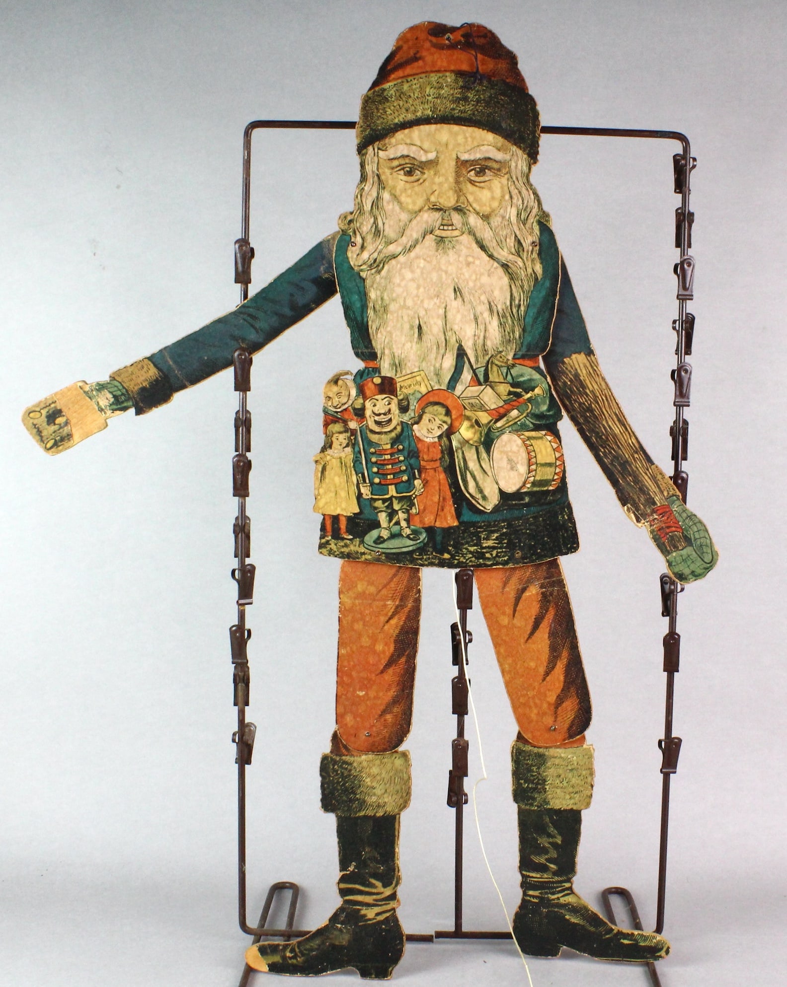 Victorian Jointed Santa Display: Victorian Jointed Santa Display. Paper board Santa Claus with jointed limbs c. 1870. 26 inches tall. Has a pull string to move the arms and legs. Translation on back reads:The old gentleman is still i