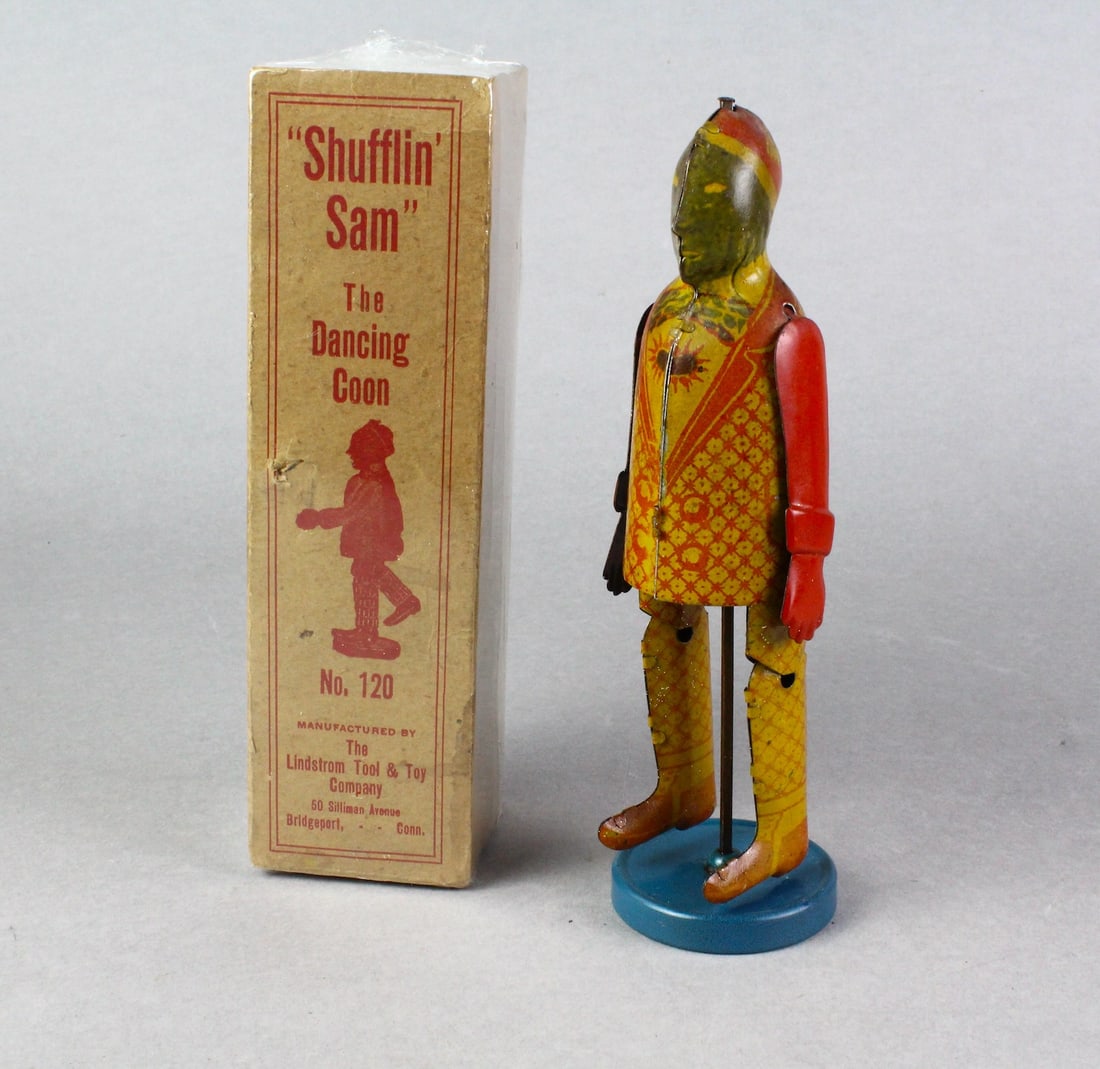 Lindstrom Shuffling Sam Dancing Man In Box: Lindstrom Tin Shuffling Sam Dancing Man In Box. 1930s tin platform tap dancing toy. Excellent condition, box has some damage on one side, but is nicely preserved in shrink plastic.
