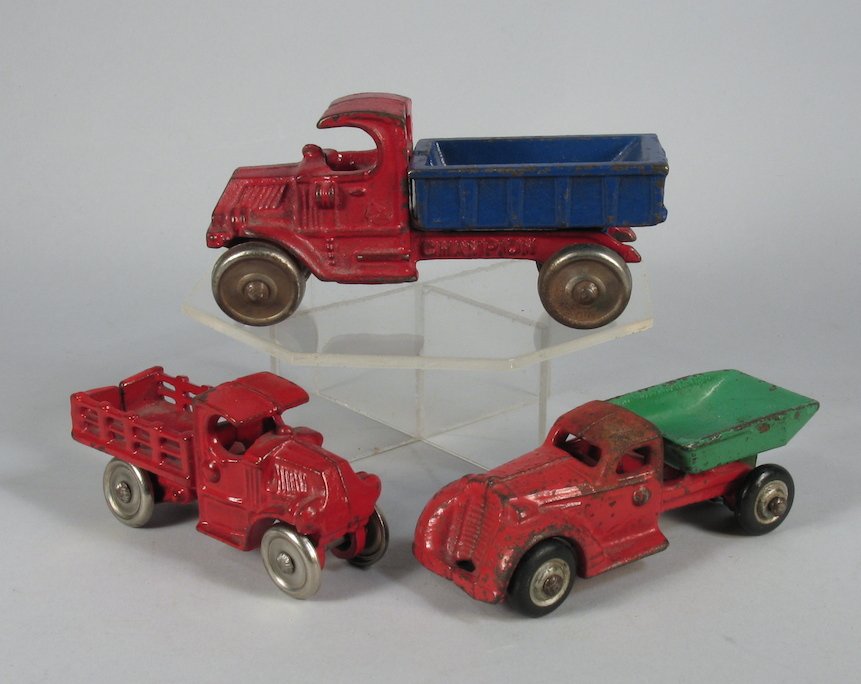 3 Cast Iron Work Trucks Hubley & Champion: Champion Blue and red Mack dump truck and 2 Hubley trucks, one a Mack stake truck and the other a dump truck. Largest is 5 inches long.