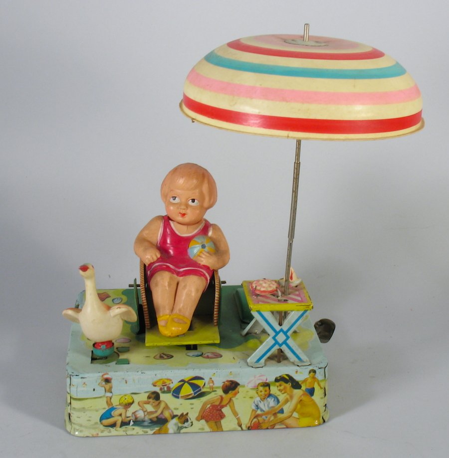 Japan Celluloid & Tin Girl on Beach With Duck by Alps: Early Alps Japan Celluloid & Tin Girl on Beach With Duck. Working wind up tin toy with spinning umbrella, rocking girl in chair and duck. Nice action, toy is 5 inches wide.