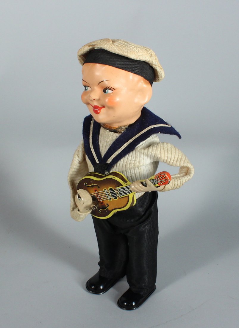 German Wind Up Sailor Playing Guitar: German Wind Up Sailor Playing Guitar. Wind up toy strums guitar and turns his head. Stands 7 inches tall. Working when tested, old glue marks at neck. Scarce toy.