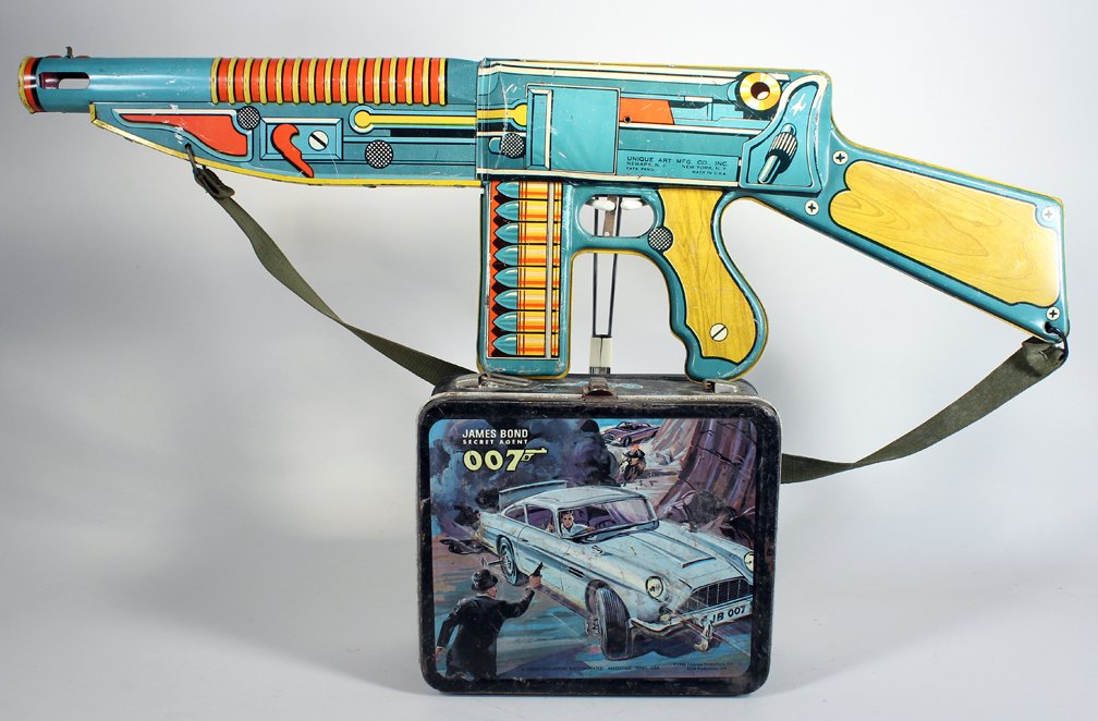 James Bond 007 Lunch Box & Unique Art Machine Gun: James Bond 007 Lunch Box & Unique Art Machine Gun. Tin litho toy gun works. Lunch box has wear and missing handle, but graphics still stand out. Machine gun is 25 inches long.