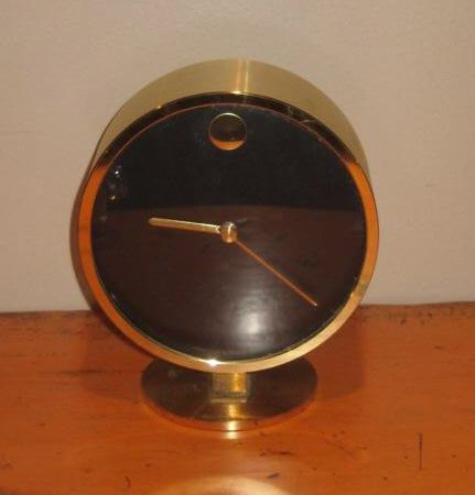 HOWARD MILLER: MUSEUM CLOCK, circular face with black dial on pedestal base, quartz movement, made in West Germany. 5 1/2 x 4 3/4 inches