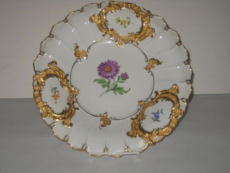 MEISSEN PORCELAIN SERVING CHARGER: Shaped gilt rim, molded three rocaille floral reserves on brim and painted floral spray in the center, crossed swords mark, 20th century. Diameter 11 3/4 in.