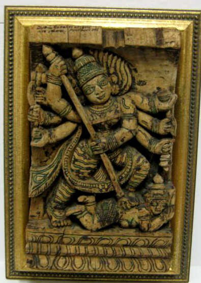 CARVED WOODEN PLAQUE OF HINDU DEITY DURGA: Rectangular block carved in high relief presenting a figure with eight hands holding various weapons and slaying demon, circa 19th/20th century, ink stained, framed. 11 5/8 x 7 1/8 in. Note: Found in 