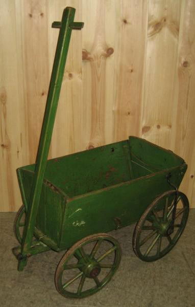 ANTIQUE ENGLISH DIMINUTIVE GREEN PAINTED CART: Solid board construction to the tapering bed, fitted slid-out back board, on steel bound wooden spoke wheels, "T" form pull handle. Full length 58 in.