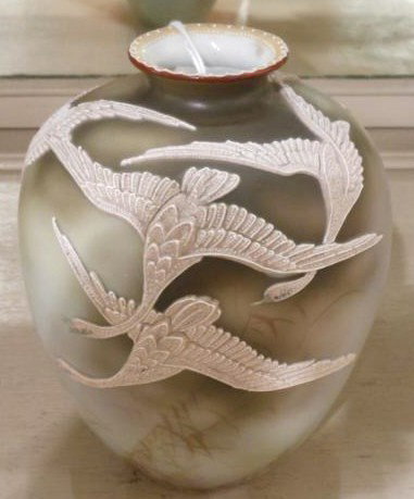 NIPPON MORIAGE VASE: Decorated in relief with five swans in full flight on smoky gray ground with painted grass, green Maple leaf mark, circa 1891. Height 6 1/4 in.