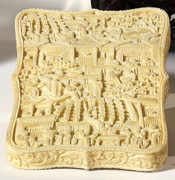 CHINESE IVORY CARD CASE: Shaped-rectangular, finely carved with figural scenes amidst trees and pagodas, oval monogrammed medallion in a center, 19th century. 4 1/4 x 2 5/8 in.