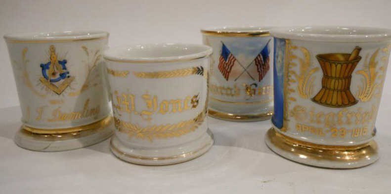 FOUR PORCELAIN SHAVING MUGS: Masonic, American flags, Mortar and pestal and G.M. Jones, two with imperfections.