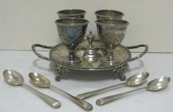 HENRY WILKINSON & CO., LONDON MARK, 1872: Sterling silver egg stand, round, two-handled and footed with beaded rims, holding four egg cups together with matching spoons of later dates bearing Goldsmiths & Silversmith Co., Ltd. marks. Weight 1