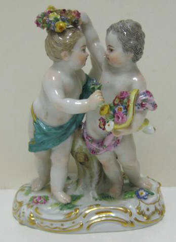 MEISSEN: Porcelain putto figure group, two children playing with flowers, one holding a wreath over the other's head (broken), #2991, crossed swords mark, early 20th century. Height 4 3/4 in.