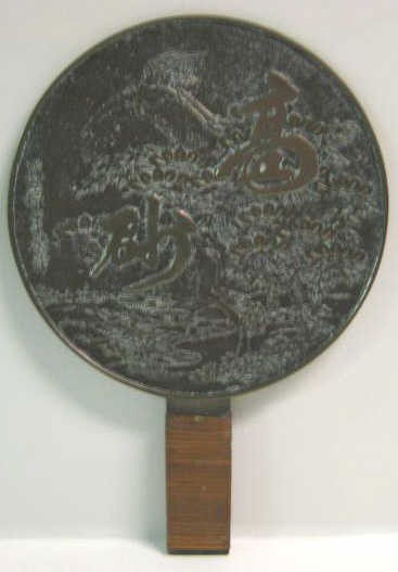 ANTIQUE JAPANESE BRONZE MIRROR: One side polished, the other with relief of characters, birds and flowers, the handle wrapped in bamboo. 11 1/4 x 7 3/4 in.