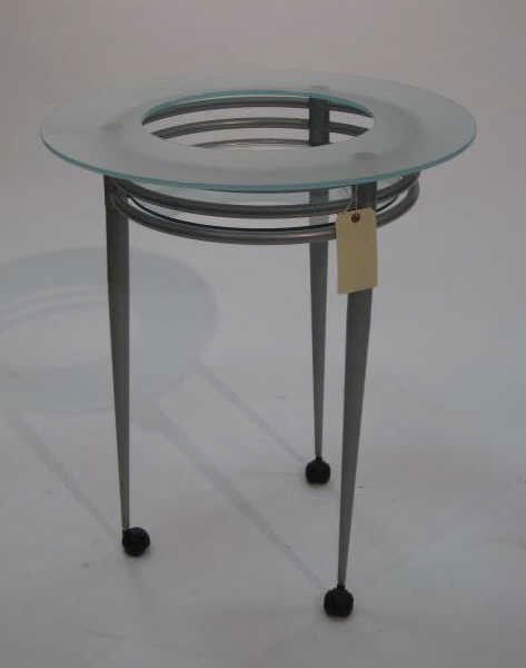 PASCAL MOURGUE FOR ARTELANO: Circular bar cart in steel and glass, open greenish tint glass ring, medial glass shelf all on a grey metal stand ending in three legs and black plastic casters. 30 x 25 1/2 inches Retail Price: $ 580
