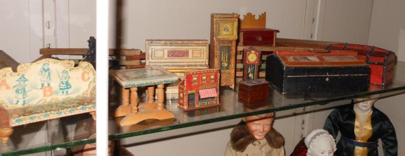 COLLECTION OF PAPER ON WOOD DOLL FURNITURE: Including piano, two clocks, two trunks, sofa, table, Market store, small box with long folding wooden fence, two-drawer chest and carved wood horse-drawn cart, total 12 pieces.