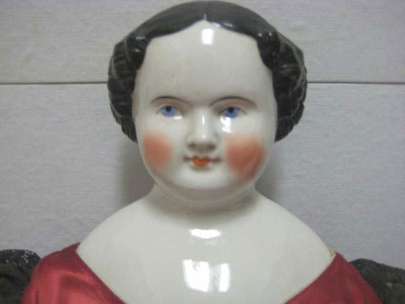 29" CHINA SHOULDER-HEAD DOLL: Black painted 'flat-top hairdo, blue eyes, cloth body with glazed arms (crazed) and legs with molded and painted boots, wearing red silk dress.