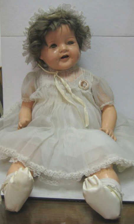 27" IDEAL SHIRLEY TEMPLE BABY DOLL: Composition head on shoulder plate, arms and legs, flirty green eyes, open mouth with two upper and three lower teeth, cloth body with cry voice box, white organdy dress and bonnet, ST pin button, mar