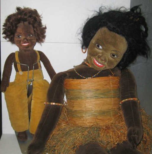 36" & 18" NORAH WELLINGS BLACK ISLANDER DOLLS: Stuffed brown velvet, molded mask face with glass eyes , painted smiling lips and teeth, wearing original raffia skirt and bodice, ring earrings, beaded necklaces and bracelets on arm and leg together