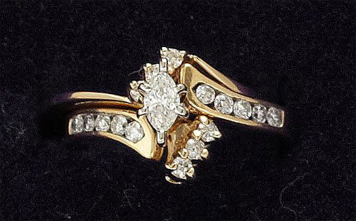 Diamond Bridal Set: 14k yellow gold engagement ring set with one marquise cut center diamond flanked by ten round brilliant cut diamonds accompanied by a wedding ring jacket set with six round brilliant cut diamonds weig