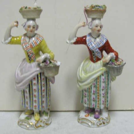 TWO MEISSEN PORCELAIN FIGURES: Peasant women with baskets of flowers, each similar but in different colors, bearing crossed swords marks underglaze, imperfections, 19th century. Height 6 in.