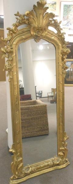 ANTIQUE FRENCH GILT WOOD PIER MIRROR: Scrolling foliate crest with Rococo motifs, over the arched mirror plate, with convex reeded pilasters and similar decoration below. Height 81 1/2, width 35 in.