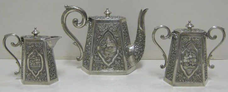 CHINESE EXPORT THREE-PIECE SILVER TEA SET: LATE 19TH CENTURY A set containing teapot (5 3/4"), milk jug (4 1/2") and sugar urn (5"), each piece hexagonal tapering form with lids, two relief lozenge-shaped medallions of landscape and vacant shi