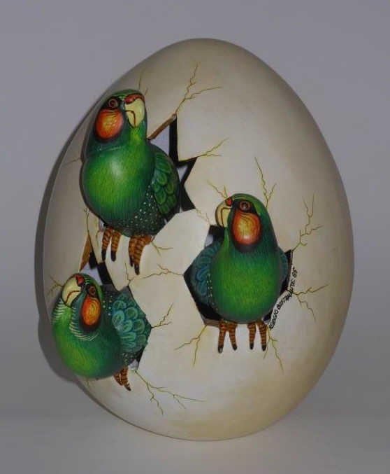 SERGIO BUSTAMANTE, MEXICAN (B.1942): Three parrots emerging from an egg, glazed and painted ceramic, signed and dated 85. 10 inches