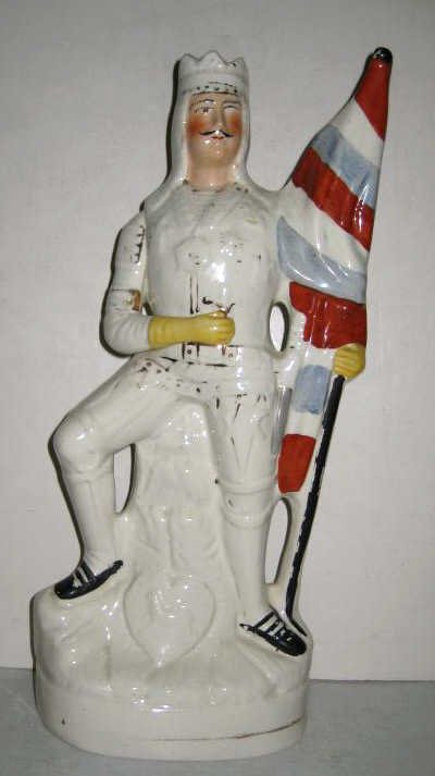 STAFFORDSHIRE THEATRICAL PORTRAIT FIGURE: Georg Rignold as King Henry V, standing and holding flag, oval base, late 19th century. Height 15 8/2 in.