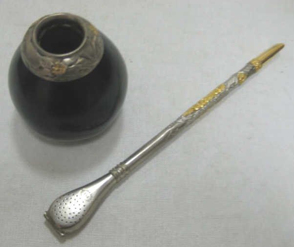 INDUSTRIA ARGENTINA YERBA MATE CUP AND STRAW: A straw (bombilla) made of .800 silver and 18K gold floral decoration and mouthpiece with unscrewed strainer together with silver and gold mounted gourd cup, 19th/20th century. Straw length 8 in; weig