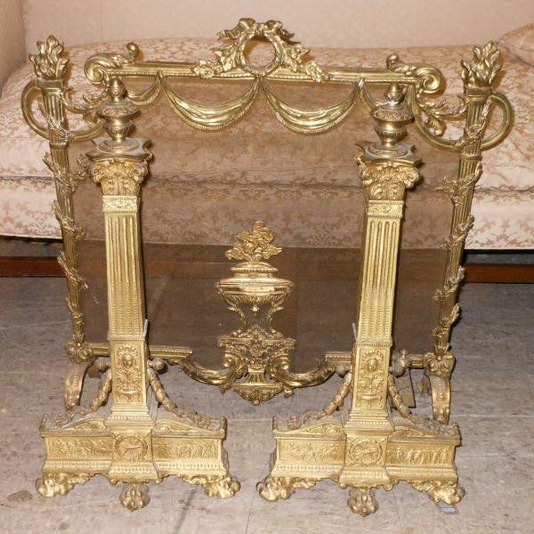 THREE PIECE FRENCH LOUIS XVI BRASS FIREPLACE SET: Pair of andirons with urn form finials over the square reeded columns with Corinthian capitals, with decorative festoons below, on animal form feet, height 26 in; together with the screen centering a