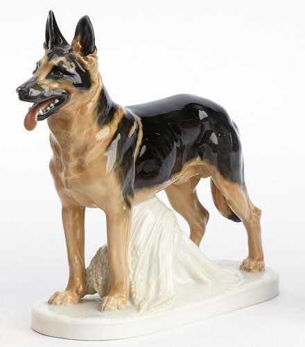 MEISSEN PORCELAIN GERMAN SHEPHERD: Originally design by Erich Hosel, naturalistically painted and glazed, standing over a sheaf of wheat, crossed swords with dot (Pfeiffer) mark, mold number V188, circa 1930. Height 7 1/4 in.