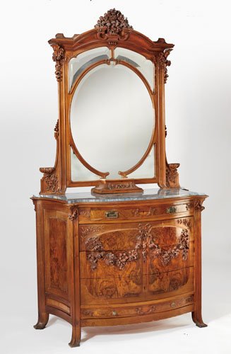 ANTIQUE CONTINENTAL ART NOUVEAU DRESSER AND MIRROR: With elaborate carved floral crest over the arched mirror holding several shaped beveled panels, over the bow front case with green inset marble top, a frieze drawer, the cupboard doors with carved fo