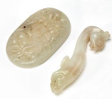 TWO SCULPTED CHINESE PALE GREEN MINERAL ARTICLES: Belt hook with bird's head terminal, 3 1/8 inches; and a oval relief carved plaque with berries and foliage, 3 x 1 3/4 inches