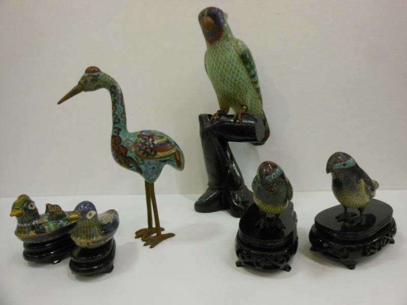COLLECTION OF CLOISONNE BIRDS: Parrot with ebonized carved wood branch, pair of finches with blue, black and white coloration, two duck shaped boxes with carved wooden stands and heron. Heights: 10 1/2 inches, 3 inches, 2 inches an