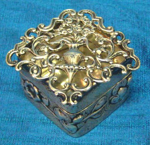 WILLIAM COMYNS & SONS FOR TIFFANY & CO.: Art Nouveau sterling silver small square scent box with floral urn and scroll openwork lid; the box chased with floral band, London hallmarks, 1911. 1 x 1 3/4 in, weight 1.25 troy ounces.