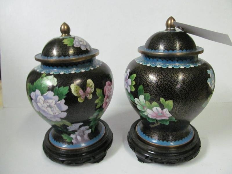 PAIR OF LIDDED CLOISONNÉ GINGER JARS ON STANDS: Peony and butterfly imagery with a black ground and blue and yellow detailing on rim, base and lid. Lid with brass ball finial. Height: 11 inches