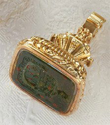 BLOODSTONE SEAL PENDANT/FOB: 14k yellow gold seal set with a bloodstone measuring 3/4 inch x 5/8 inch. Bloodstone has an intaglio depicting a crest. 1 1/4 inches high. 20.4 grams.