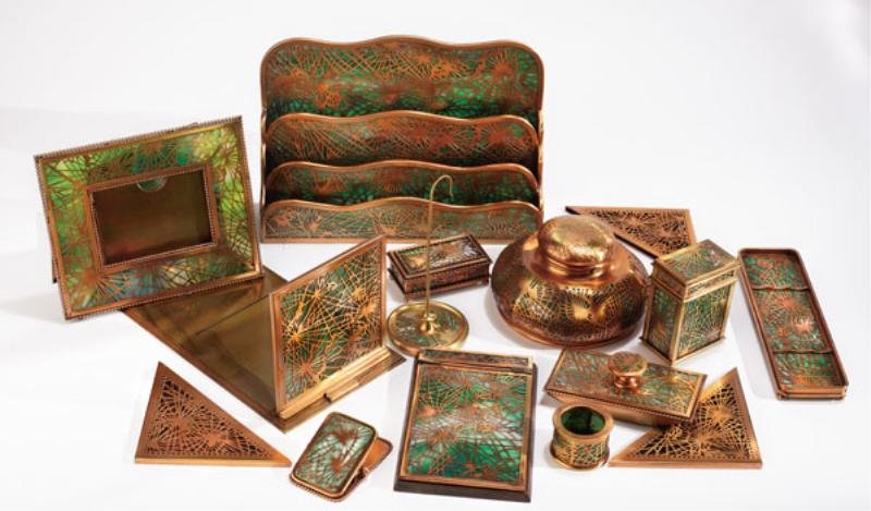 TIFFANY STUDIOS, NEW YORK: Sixteen-piece bronze mounted green slag glass desk set in the 'Pine Needle' pattern, early 20th century, Note: Hinged notepad with broken large glass cover, one of four glass pieces on picture frame b