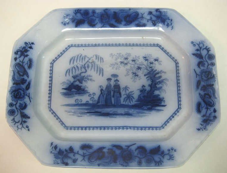 J. MADDOCK & SONS FLOW BLUE 'MANDARIN' PLATTER: Octagonal, blue transfer decoration of a couple, child and a man playing flute in landscape, flowers and shells on four sides of rim, impressed Maddock mark and blue printed pattern, circa 1950. 18 x