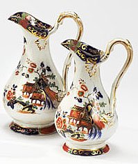 TWO ENGLISH IMARI STYLE JUGS: Each with blue underglaze, red iron and green overglaze pagodas in landscape, gilt highlights, impressed M on one, 19th century. Heights 7 1/2 and 8 1/2 in.