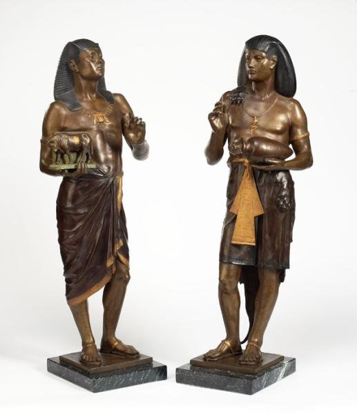 AFTER EMILE LOUIS PICAULT, FRENCH: Two bronze Egyptian figures, one holding a statue of ram, the other a jug, both signed "Picault" to base; mounted on marble plinth. Height of each 28 1/2 in.; (overall 30 in.)
