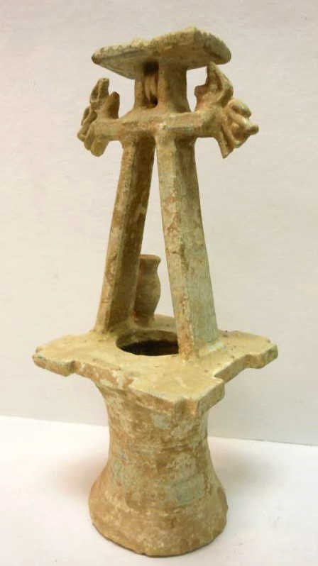 TWO CHINESE HAN STYLE CERAMIC MODELS OF WELLS: A-frame form water well with a distressed finish and celadon underglaze, possibly of the period. 17 1/2 x 7 x 7 in., 17 x 5 1/2 x 5 1/2 in.