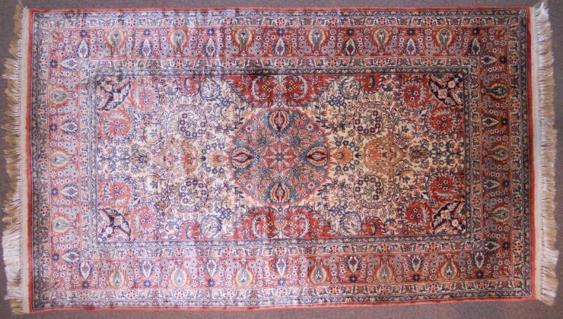 PERSIAN SILK AREA RUG: Circular blue foliate medallion centers the floral decorated ivory field with rust corners and rust border. 3 ft. x 5 ft. 1 in.