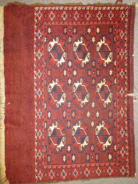 PERSIAN BALOOCH THROW RUG: Nine ivory and red geometric medallions to the brick red field, red border with latch hook guard borders. 3 ft. 7 in. x 2 ft 8 in.