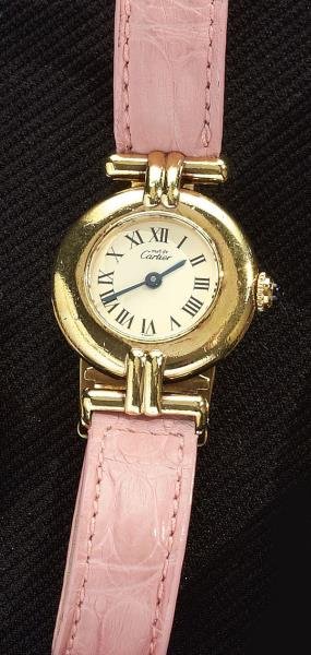 LADY'S WATCH, CARTIER: 20 micron gold over sterling round case with a quartz movement, cream dial, sapphire crown, black hands and numerals. Watch has pink leather strap with gold plated deployment buckle. (Cartier)