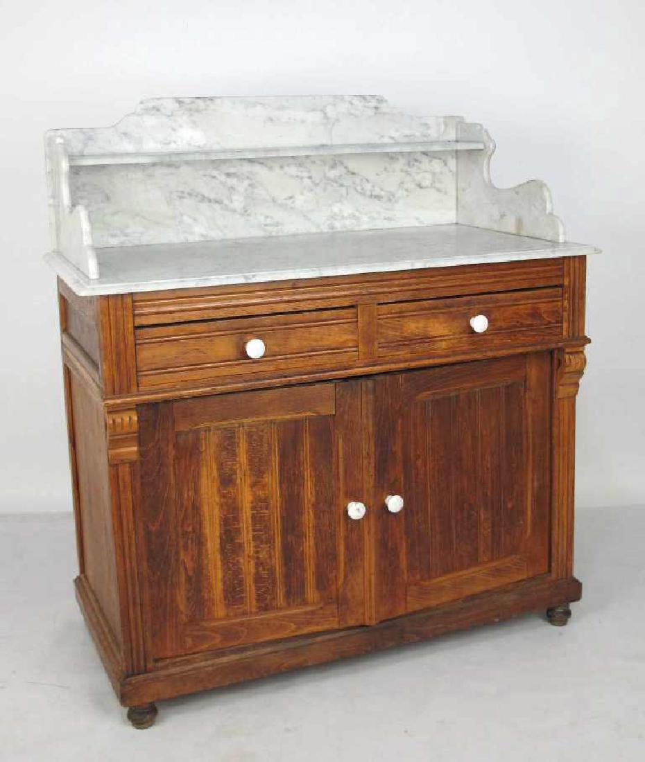 Marble Top Dresser: Dresser having 2 carved doors and 2 drawers, all with white ceramic hardware. Fluted carved detail to sides. White marble top with shelf. Light wear from age and use. 42 inches height, 39.5 inches wid