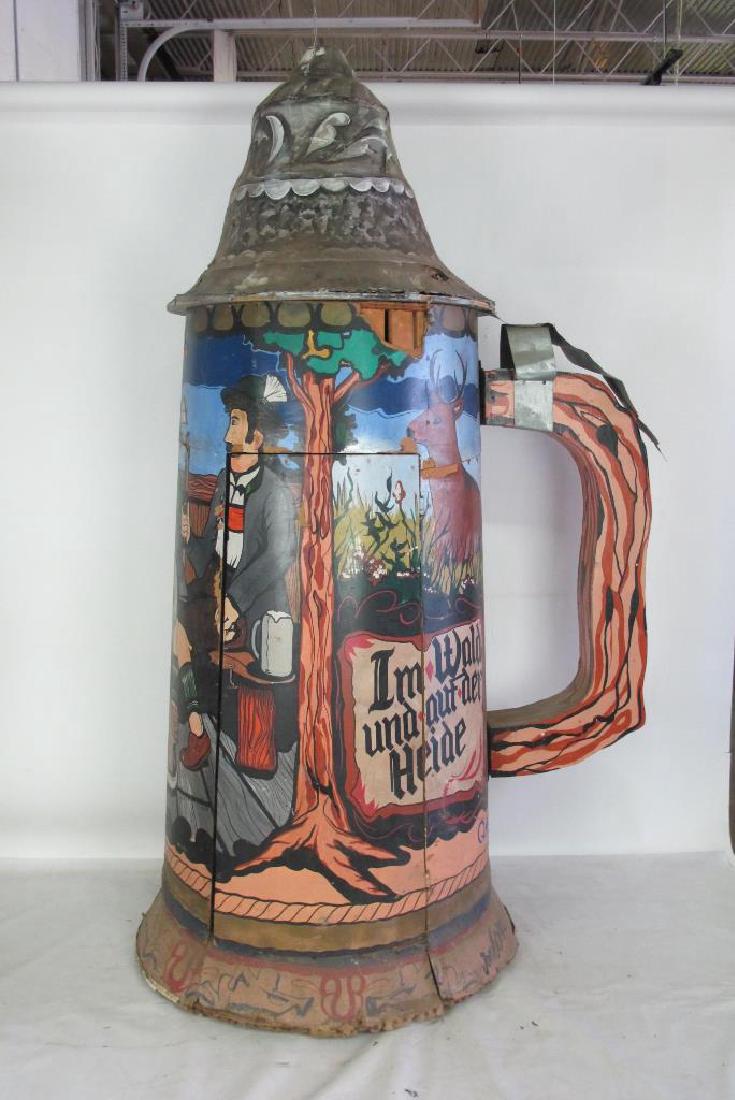 Large Beer Stein Form Piece: Large wooden piece with door and open interior. In the form of a beer stein with hand painted figural motif to sides and metal detail to handle. Side reads "Da such ich meine Freude (I look for my joy