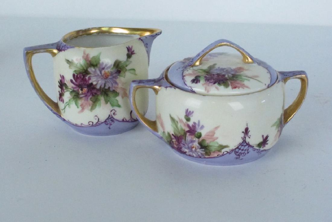 Moritz Zdekauer Porcelain Creamer and Sugar Jar: Hand painted porcelain creamer and lidded sugar jar by Moritz Zdekauer, marked MZ Austria to bottom. Painted with a floral design in dominant purple color with gilt detail. Wear to paint from age and
