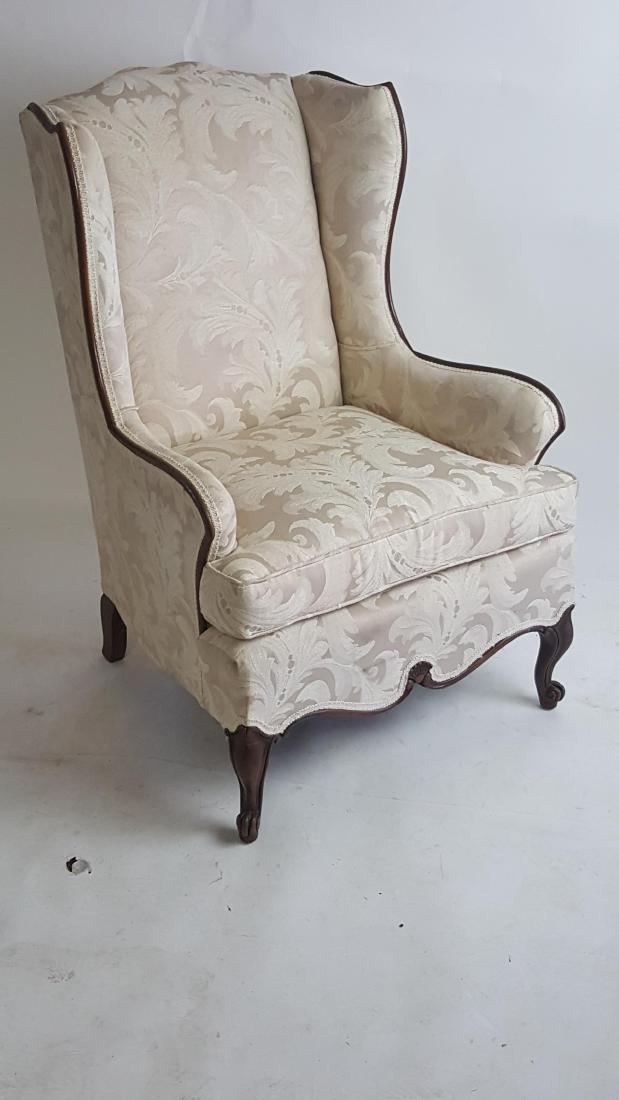 Wingback Chair: Wingback chair having carved wood frame and white, textured upholstery with foliate motif. 41 inches height, 22.5 inches width, 27 inches depth. 41"H x 22.5"W x 27"D
