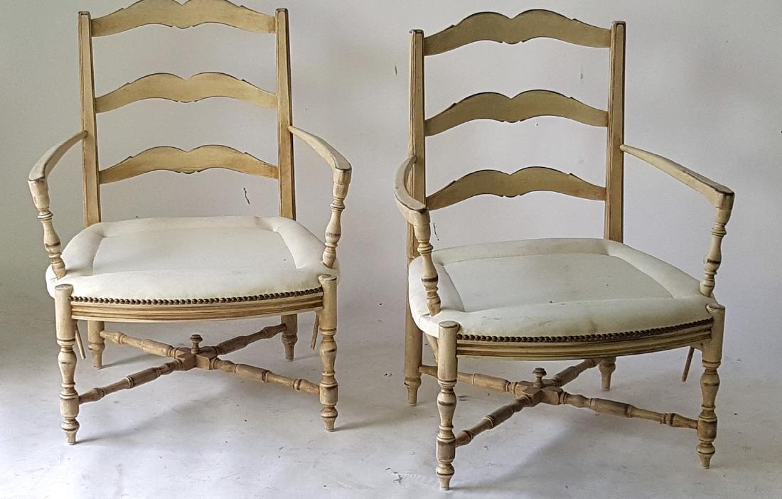 Pair of French Arm Chairs: Pair of creme peinte armchairs having white seat upholstery, a ladder back, and turned legs with stretchers. 35.5 inches height, 27.5 inches width, 24 inches depth. 35.5"H x 27.5"W x 24"D Wear from ag